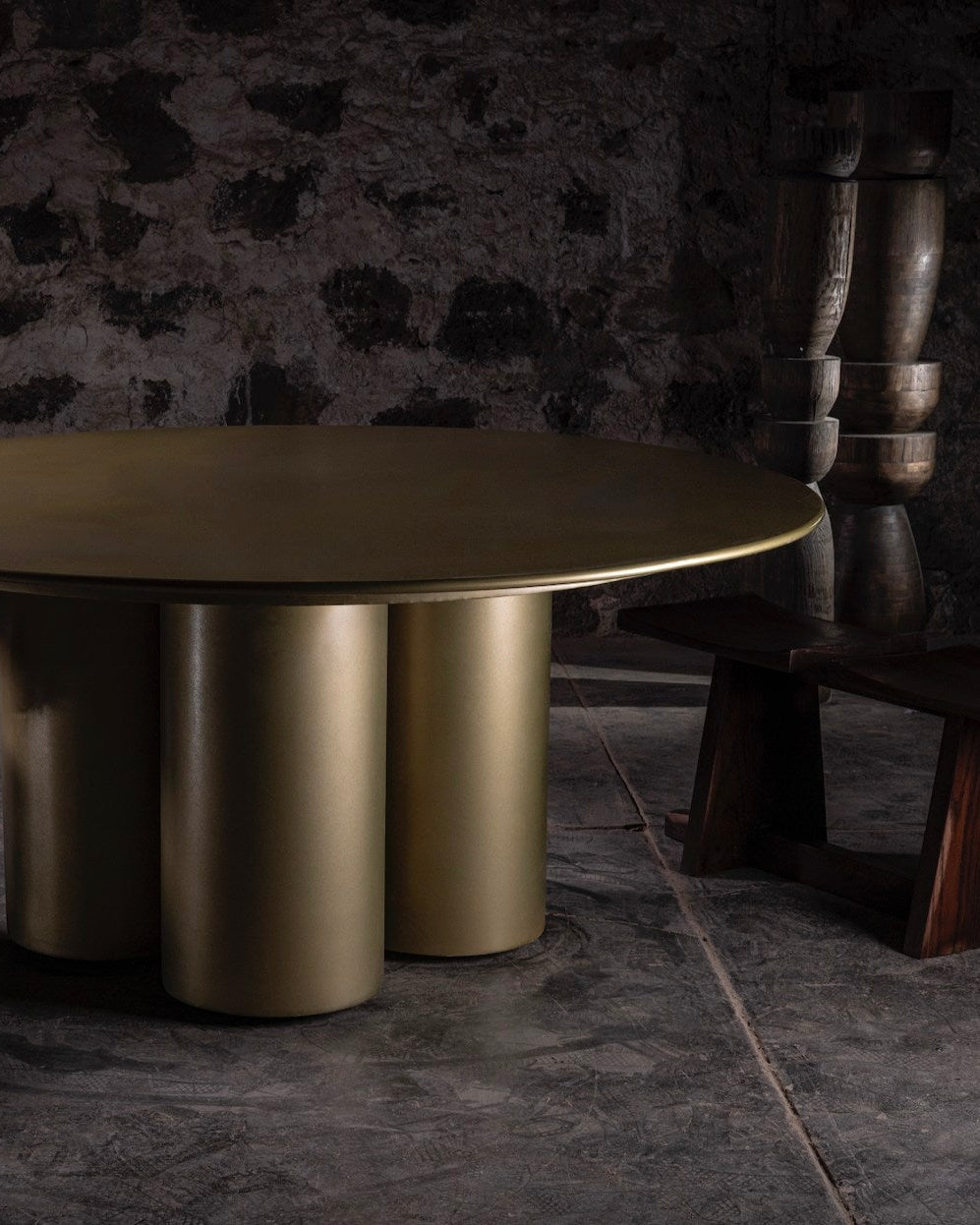 014 Steel Dining Table — side angle showing gold finish and stone wall