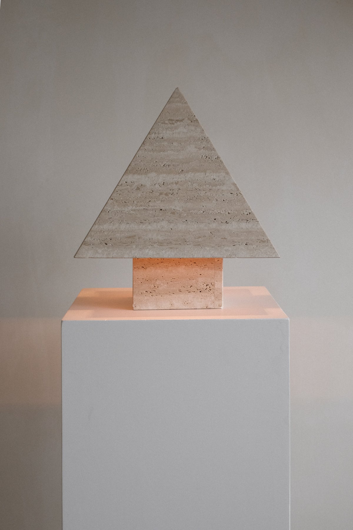 Travertine Pyramid Table Lamp — front view on white pedestal