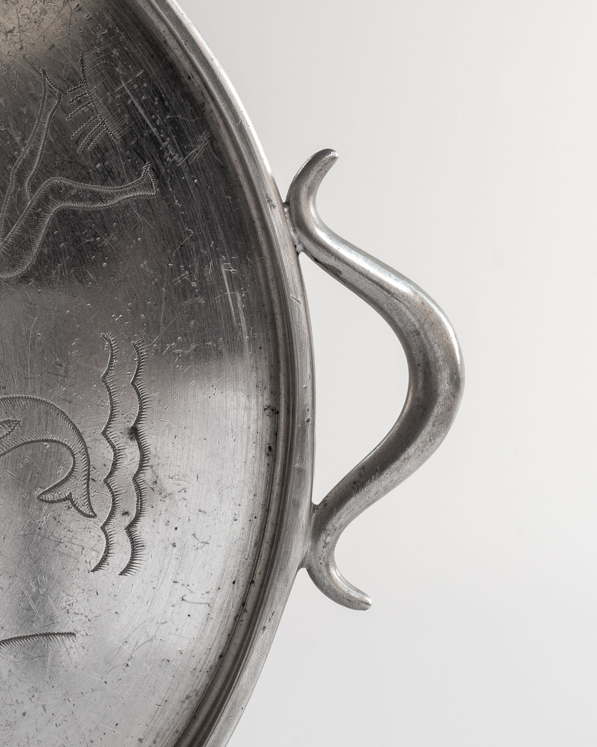 Curved handle detail of Art Deco pewter tray with engraved motifs