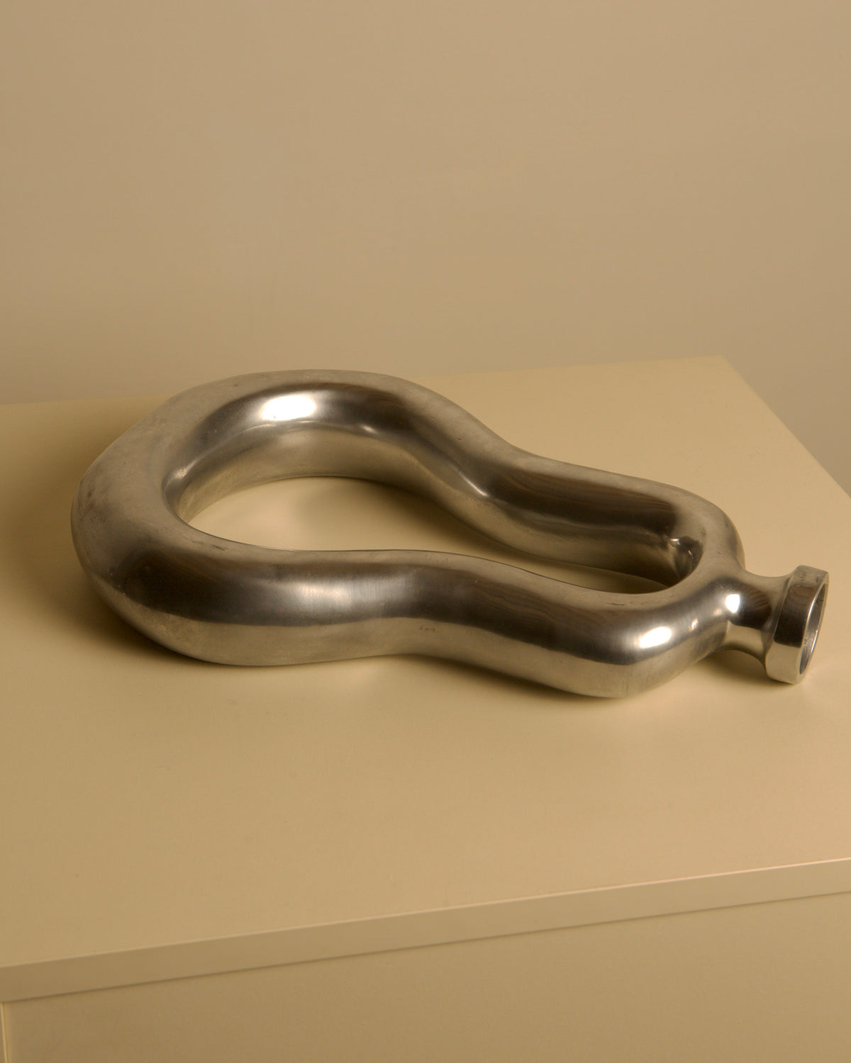 Italian cast aluminum vase 80's — angled view on neutral surface