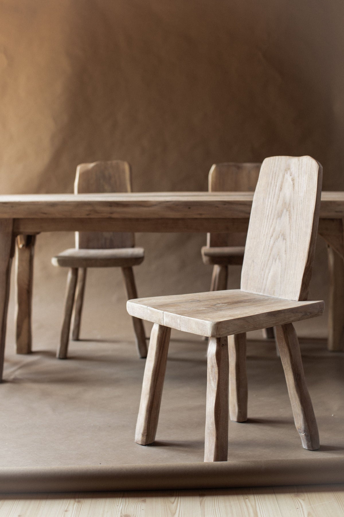 Light wood brutalist dining chair with geometric backrest and matching stools