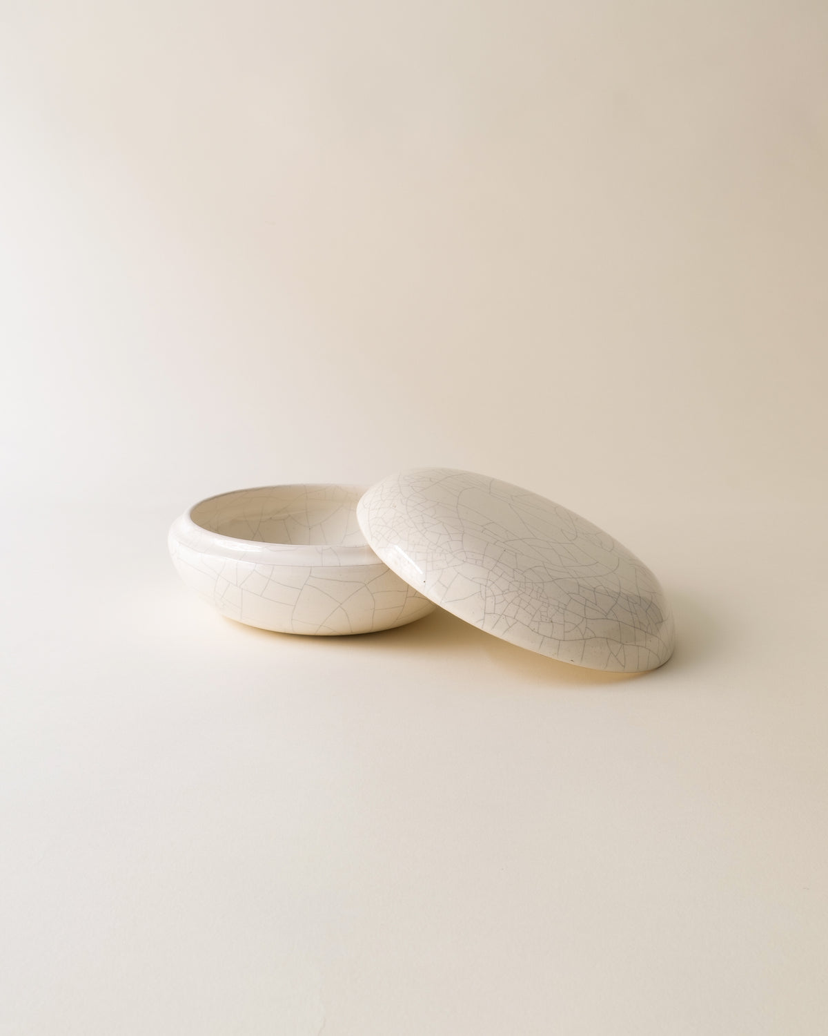 Cream ceramic jar with crackle glaze finish, lid partially open