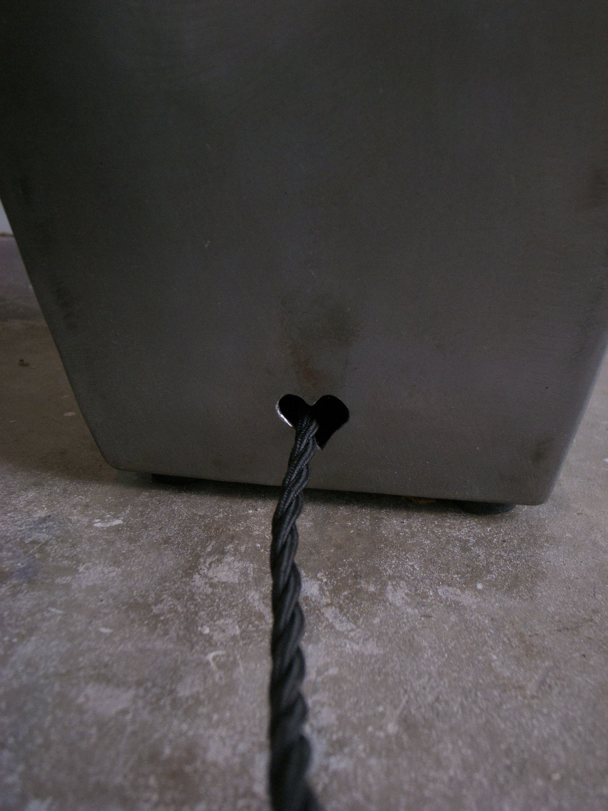 Close-up detail of black power cord connecting to steel lamp base