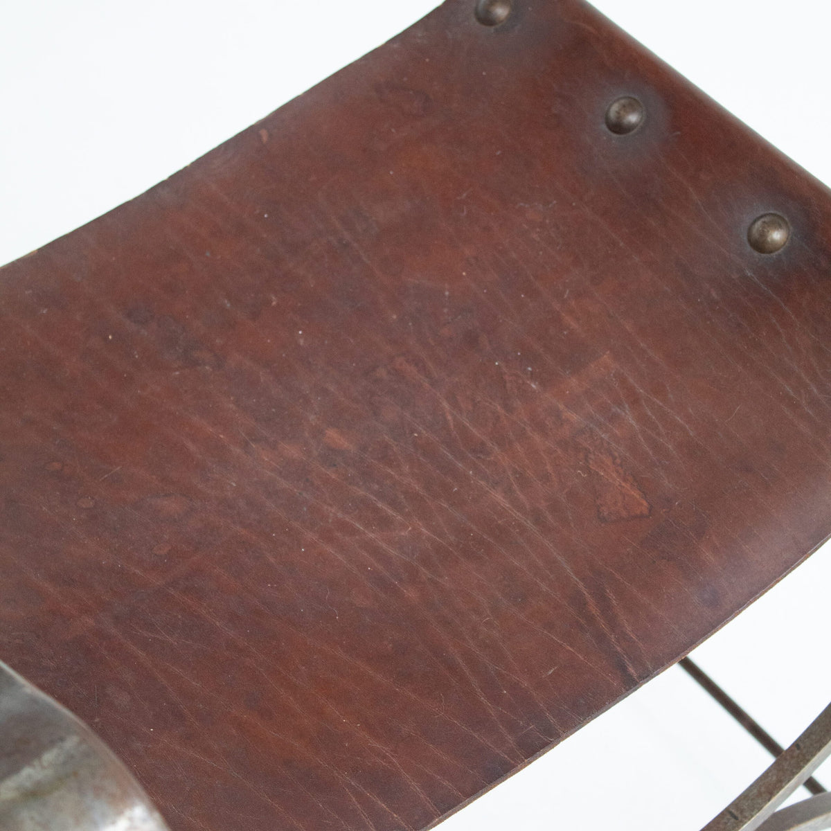 French pair of Iron Curule Chairs in Leather — close-up of brown leather seat