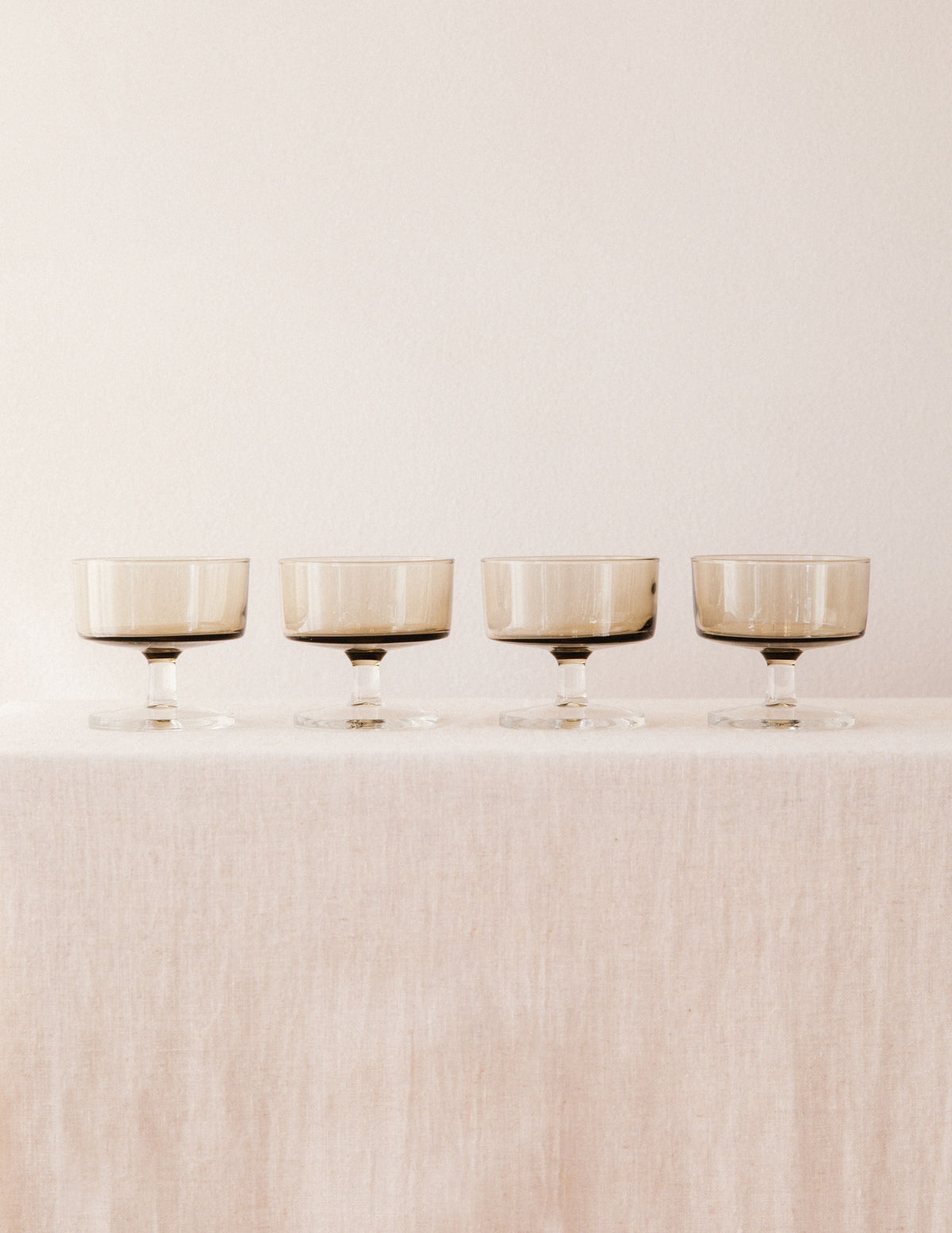 Four smoked glass champagne coupes arranged in elegant row