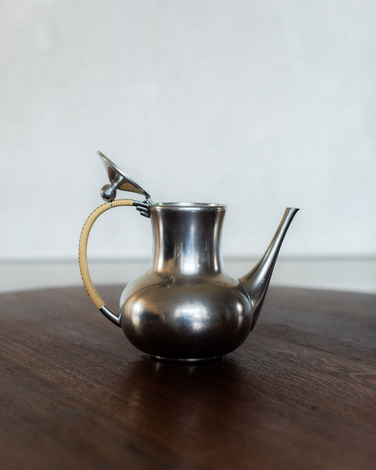 Polished pewter Art Deco teapot with rattan-wrapped handle