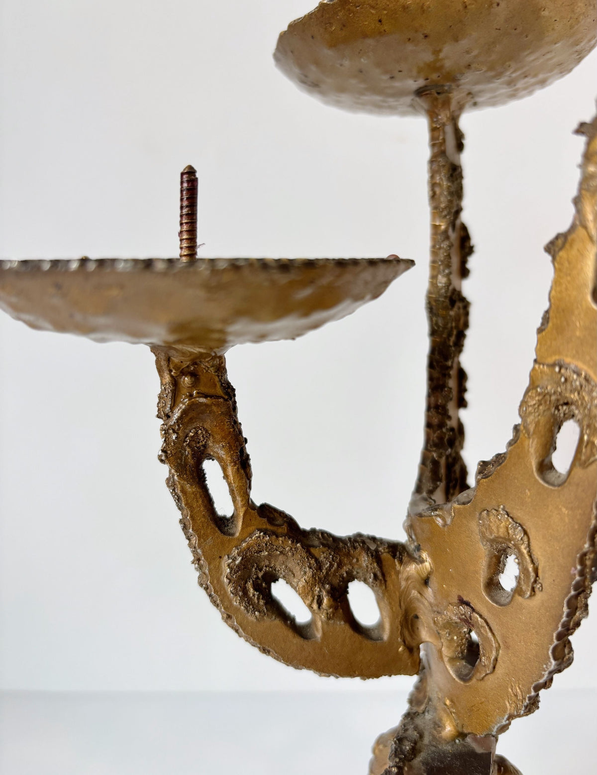 Torched brutalist metal candleholder detail showing textured arms