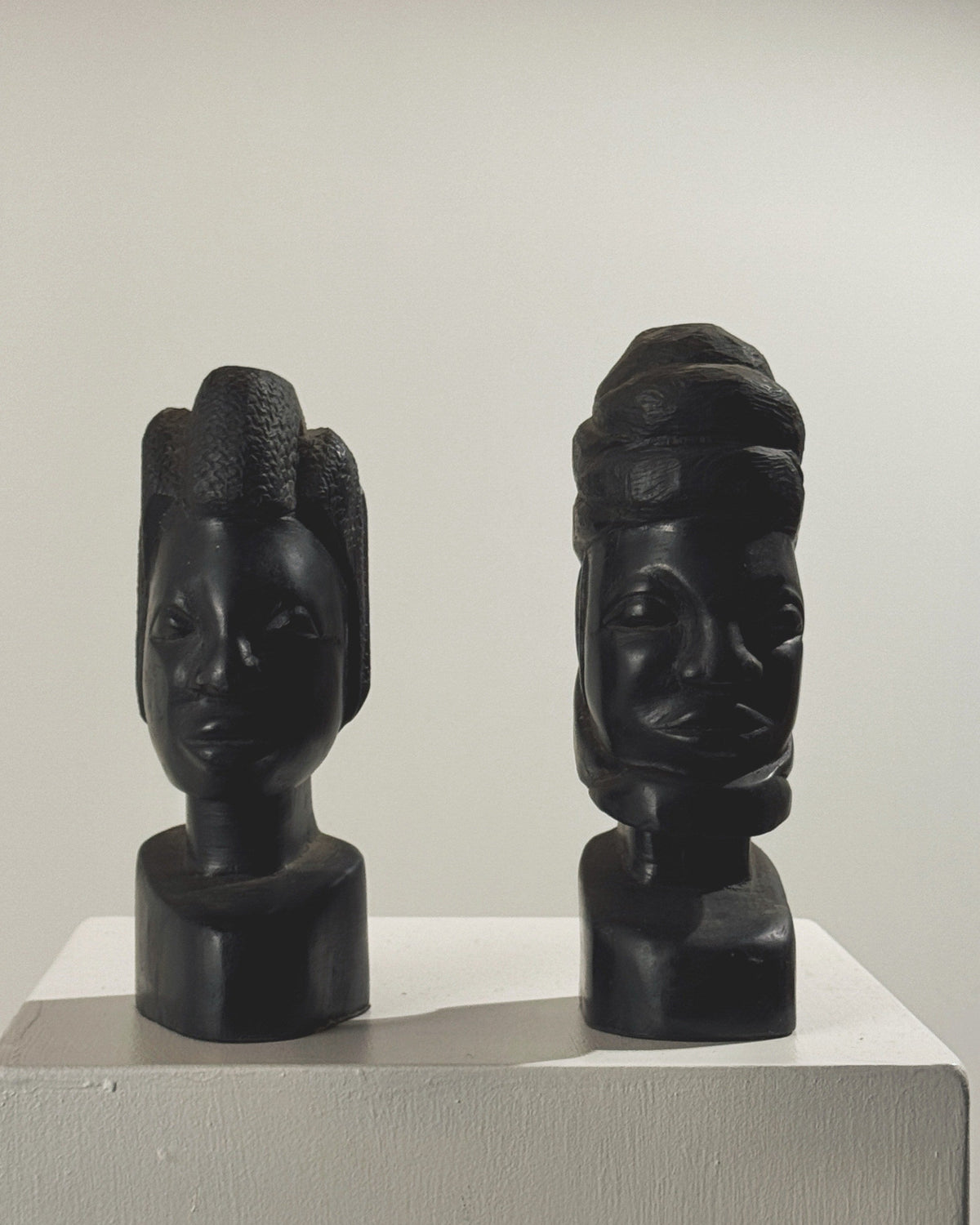 Two carved ebony African busts displaying intricate sculptural details