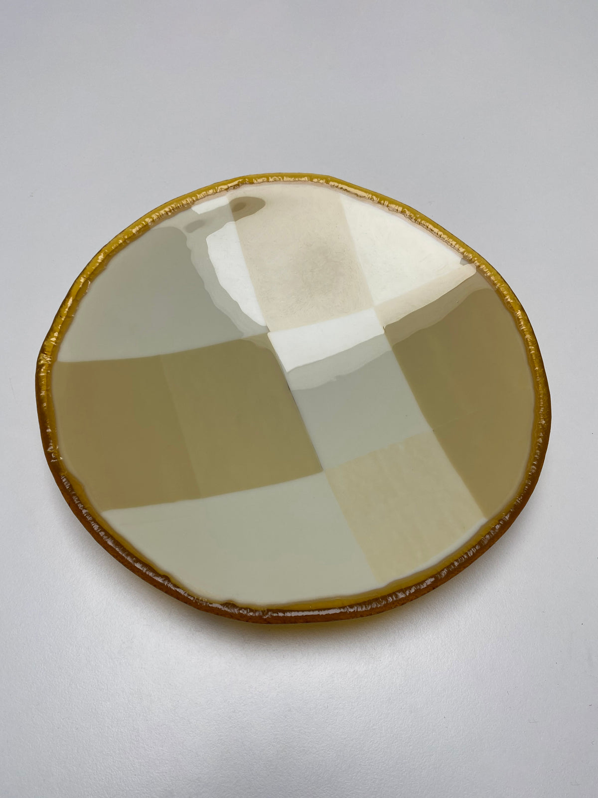 Beige checkered glass plate with amber rim detail, top view