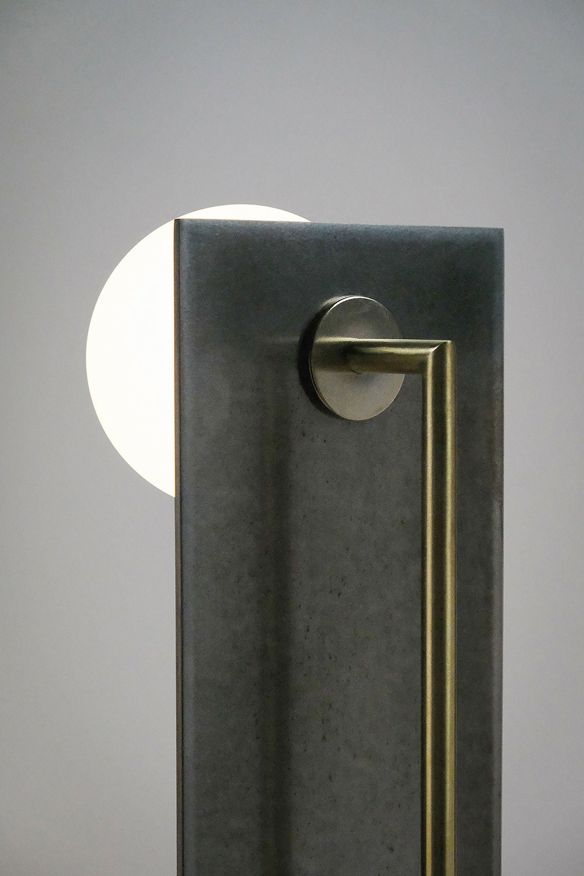 Modern vertical table lamp with dark stone base and brass handle detail