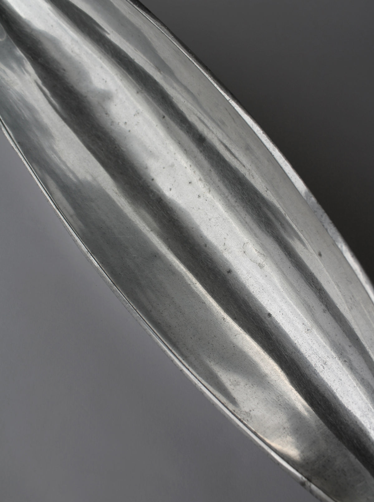 Close-up detail of polished aluminum bowl showing reflective ridged surface