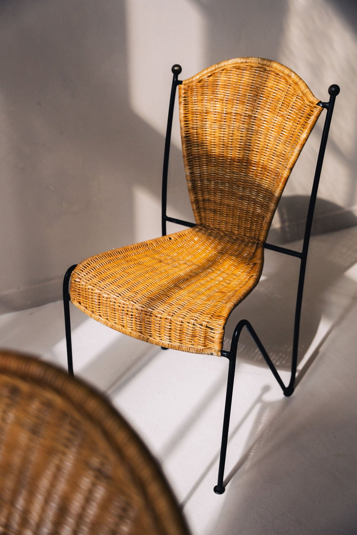 Wicker chair with black metal frame showing curved profile detail