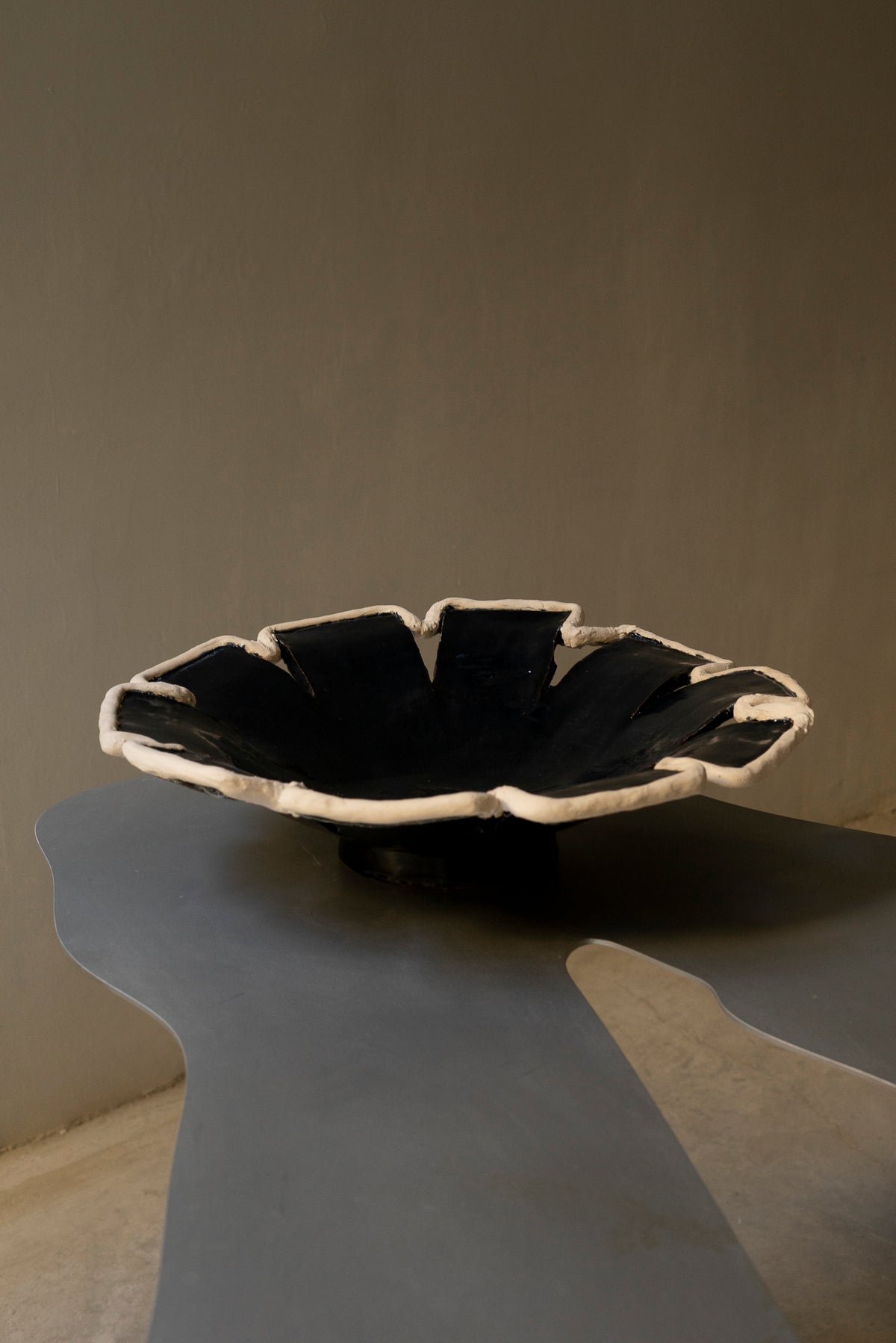 Navy blue ceramic decorative dish with white ruffled rim, pedestal base
