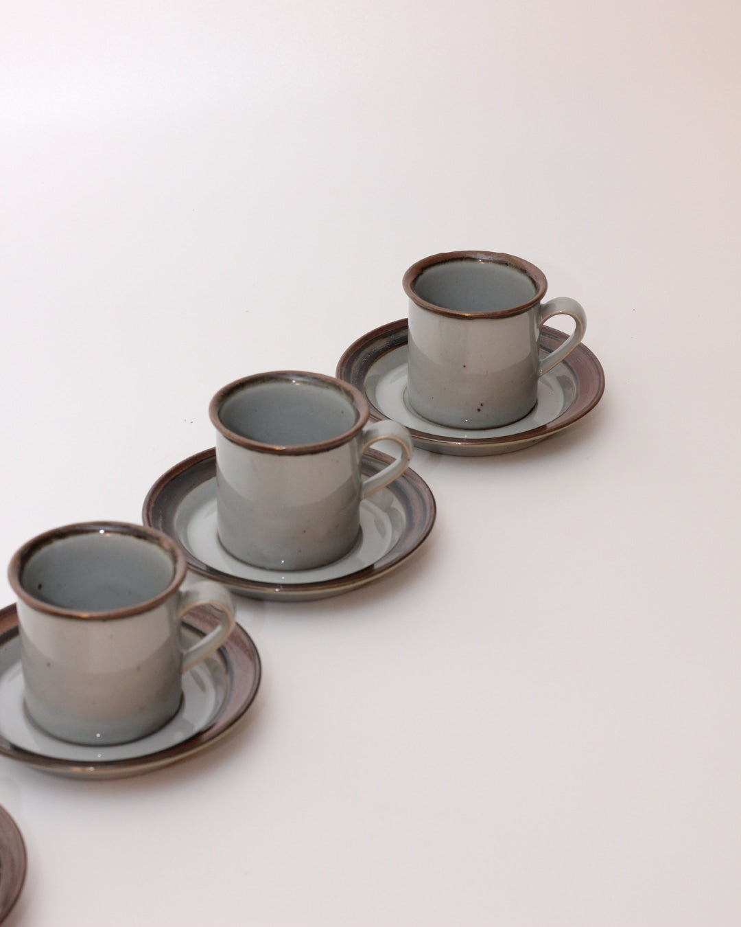 Set of Four Ceramic Cups with Saucers — arranged on white background