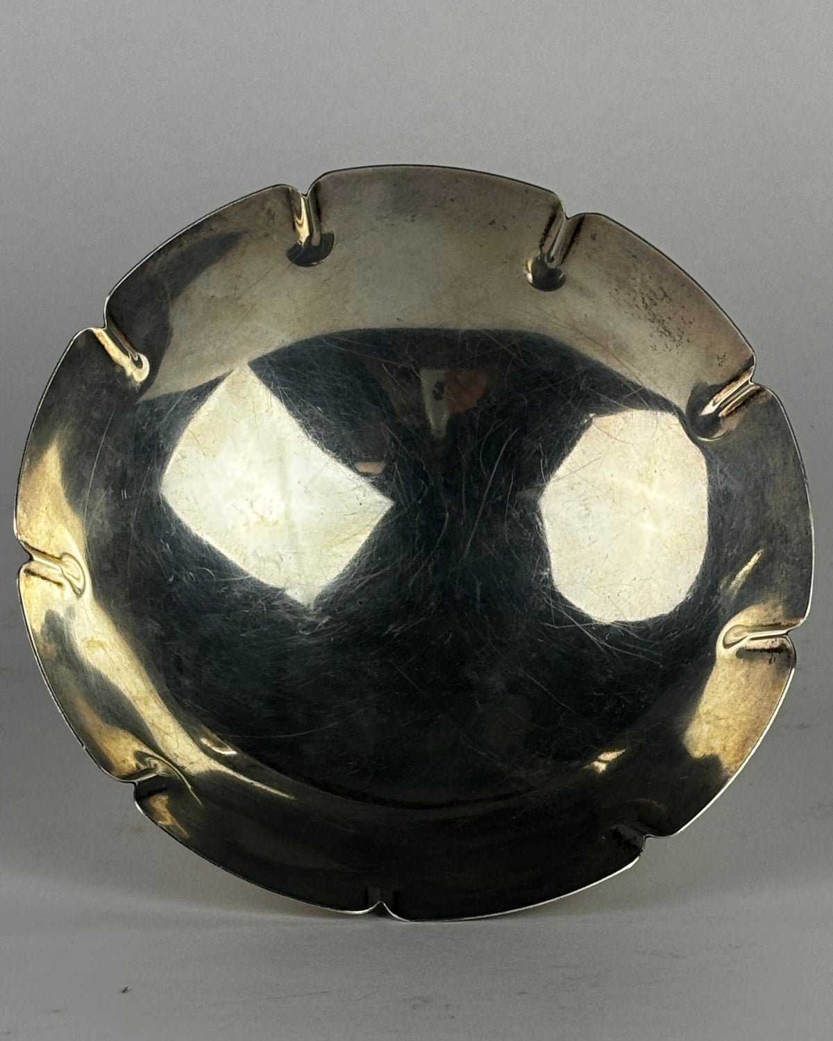 Sterling silver dish interior view showing reflective curved bowl with scalloped rim