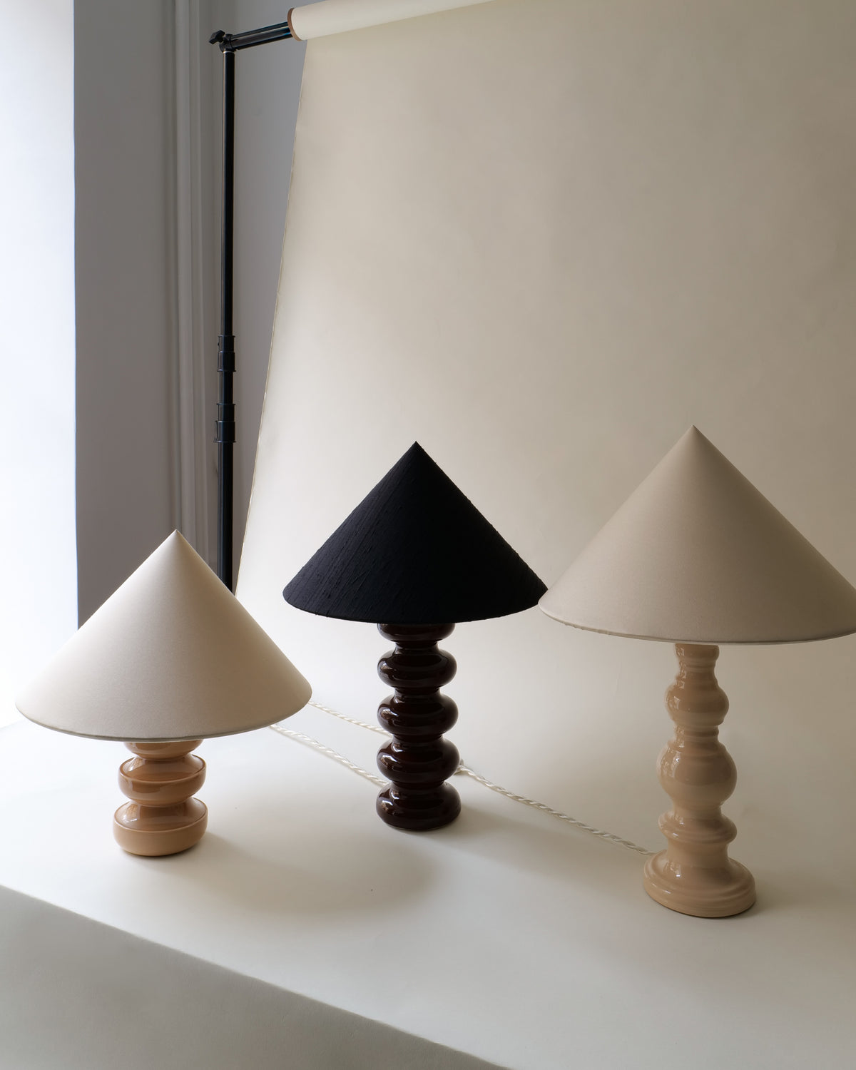 Three ceramic table lamps with conical shades in styling setup
