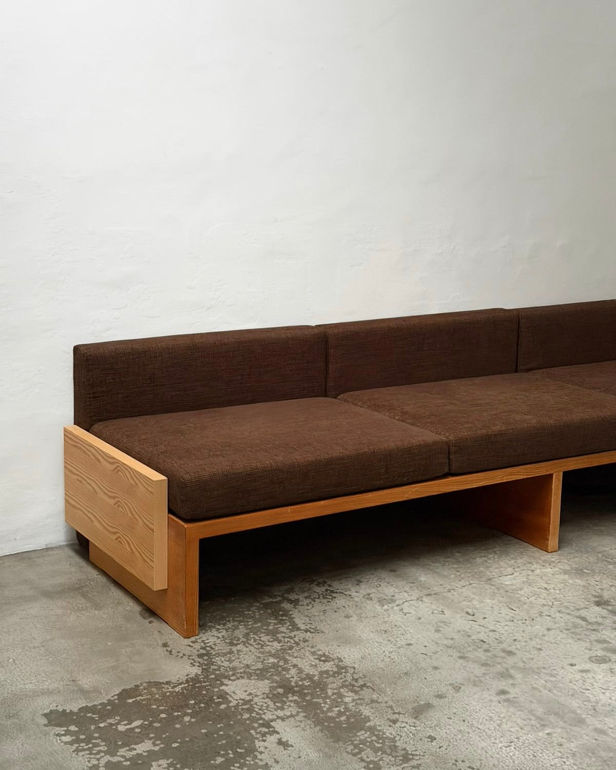 Modernist Benches and Stool, c.1970 — side view of brown upholstered sofa in minimalist setting