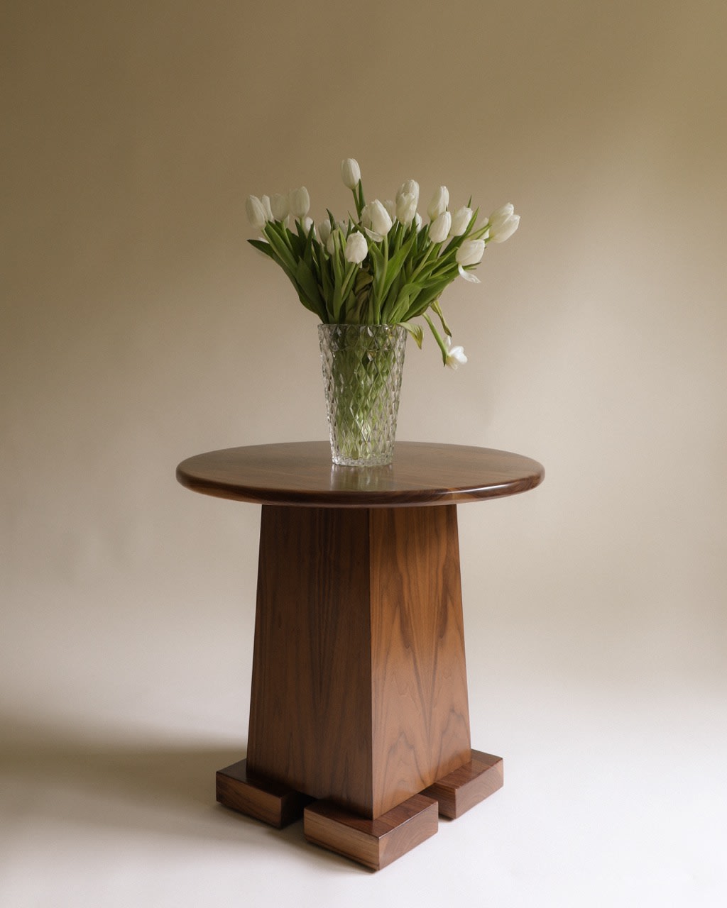 Roscoff Side Table — angled view with round walnut top and floral arrangement