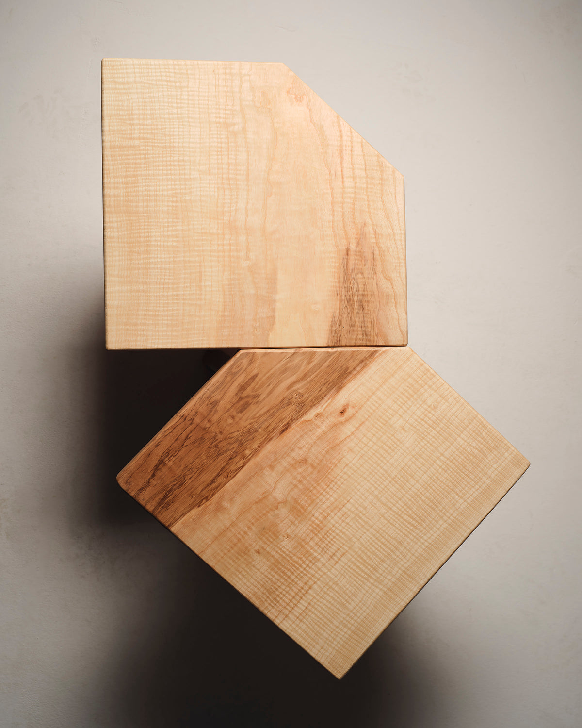 Two stacked maple wood side tables showing rich grain patterns