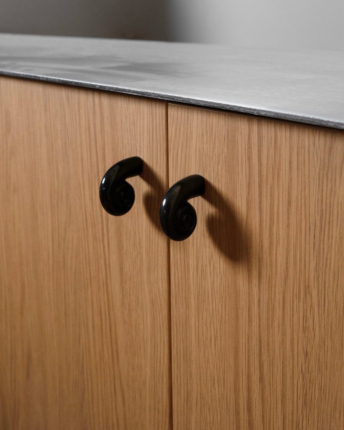Noelle Knob - Antique Brass — back view on wooden cabinet