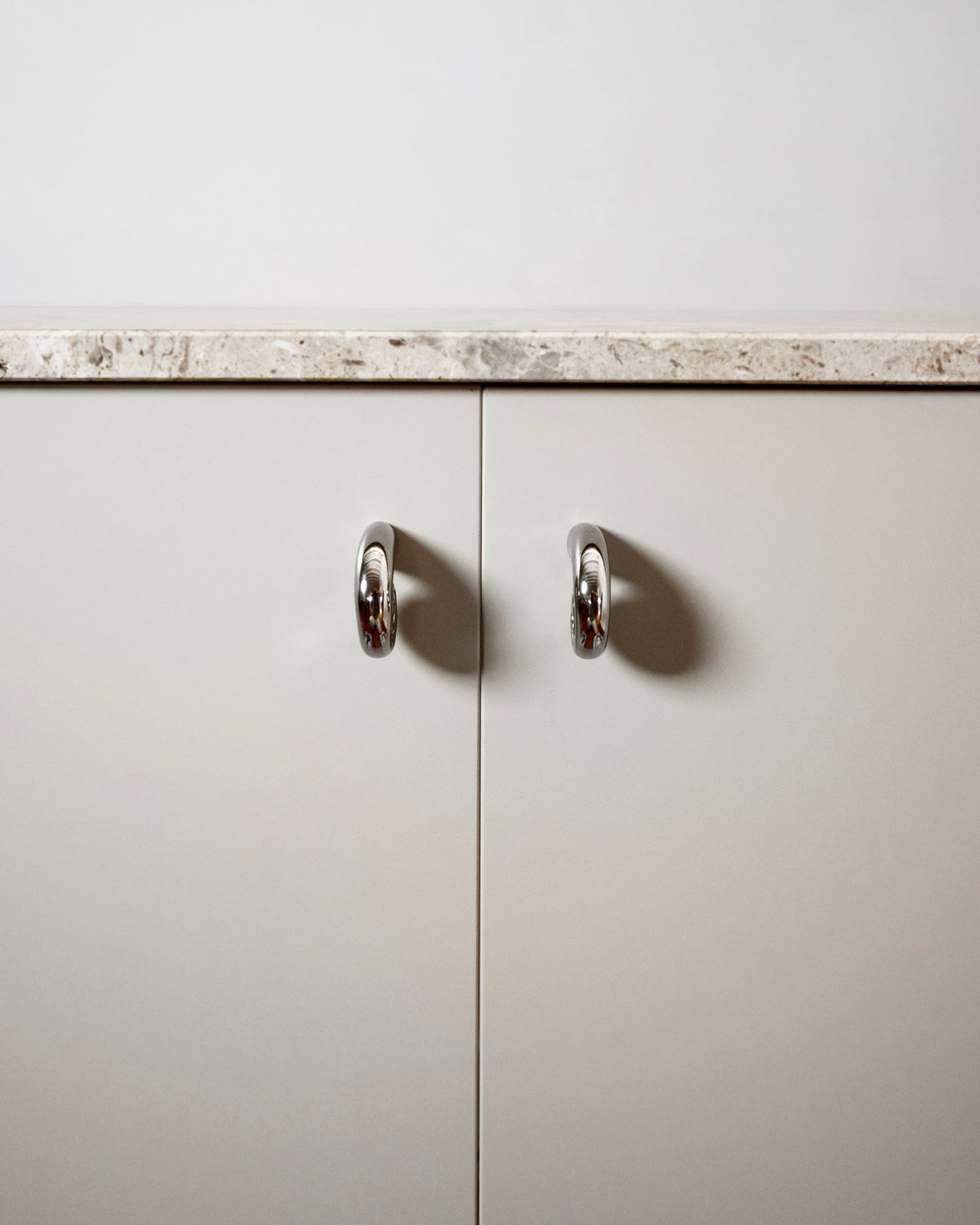 Noelle Knob - Titanium — front view on minimalist cabinet doors