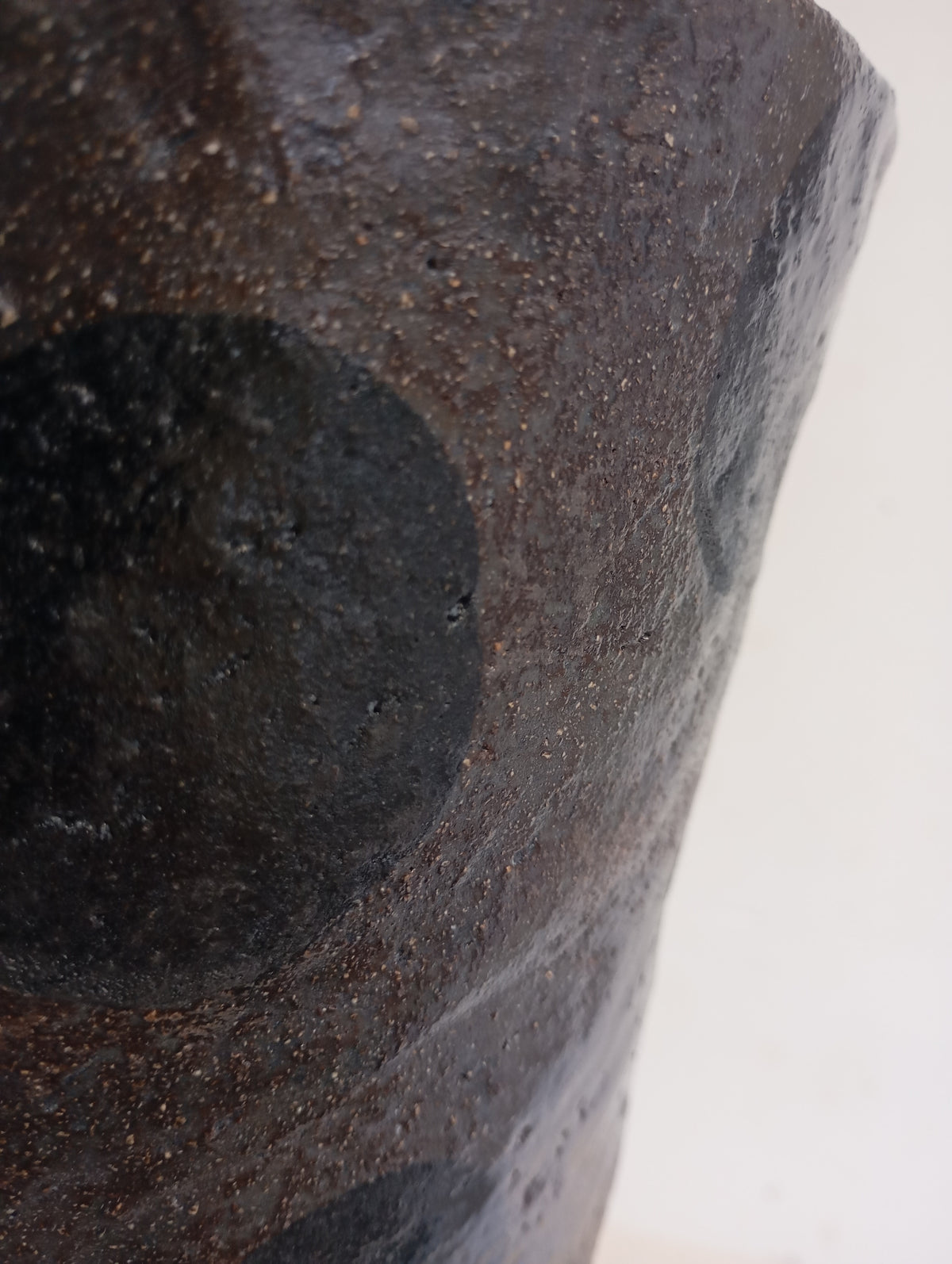 Close-up of the Claire Pain Stoneware Vase, featuring a textured dark brown finish with black circular patterns, shown against a plain white background.