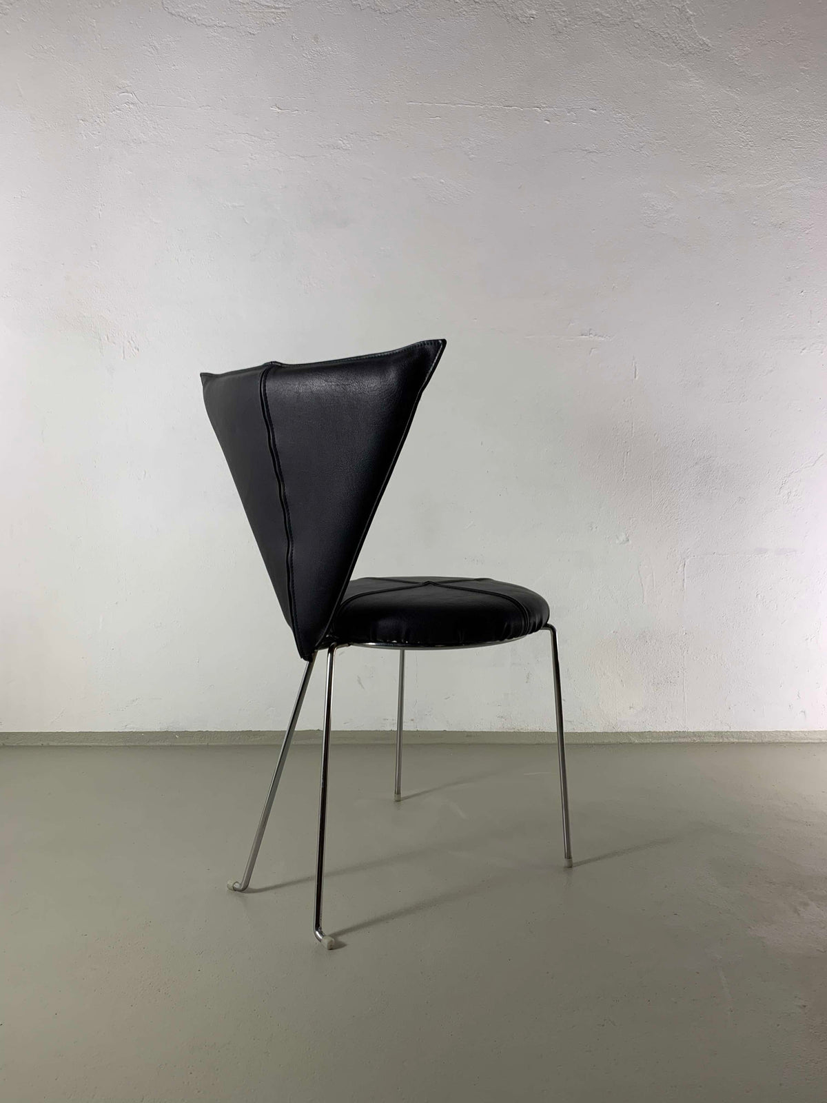 Black leather chair profile view showing curved backrest and metal legs