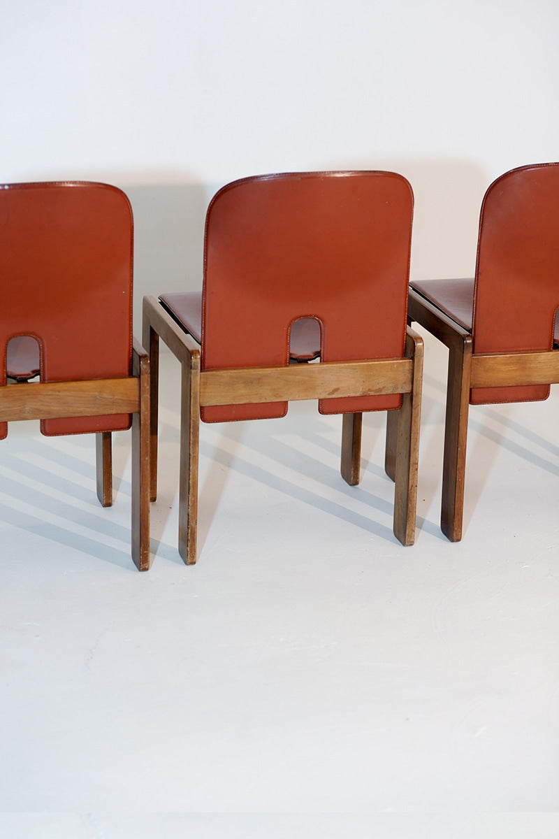 Rear view of 4 Cassina 121 dining chairs showing cognac leather backs