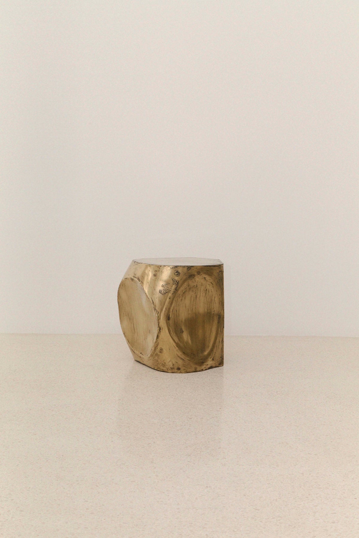 ROCHER SMALL TABLE IN POLISHED BRASS RESIN — angled view on light surface