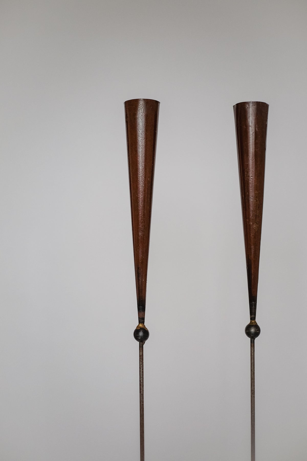 The Pieter Spruyt Copper Candle Scones by septembre studios feature two tall, slender metallic cones with narrow bases on thin rods, standing side by side against a light background—evoking vintage floor candle holder elegance.