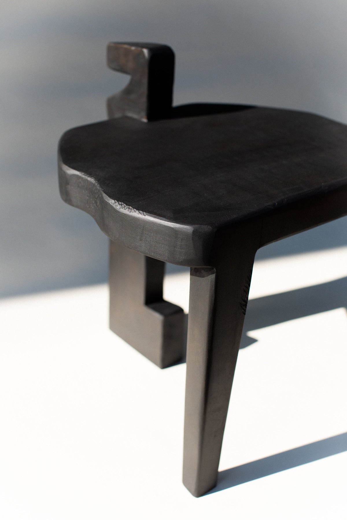 Black wooden Sharie stool with curved backrest and geometric legs
