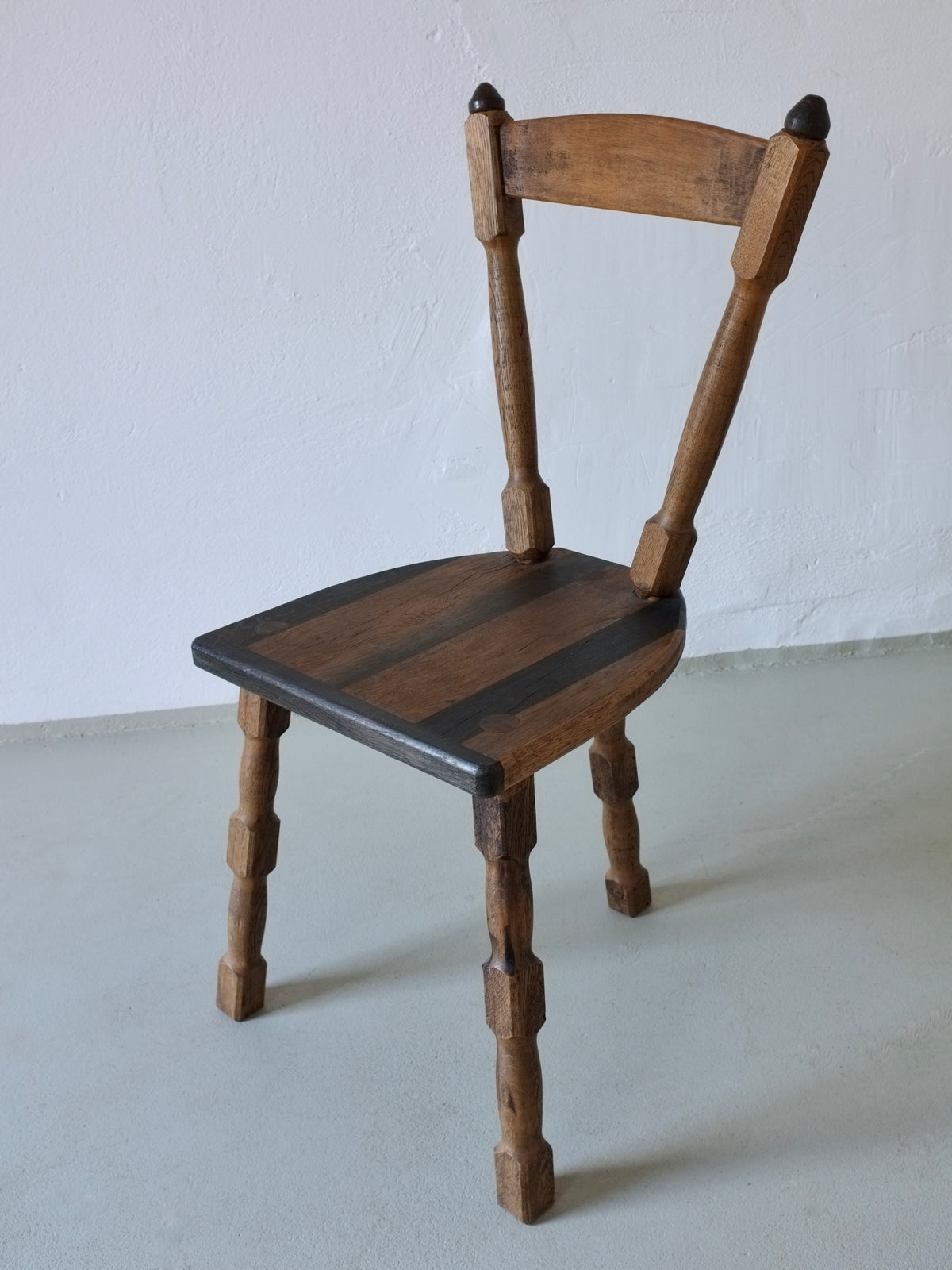 Brutalist wooden dining chair with tripod base detail view