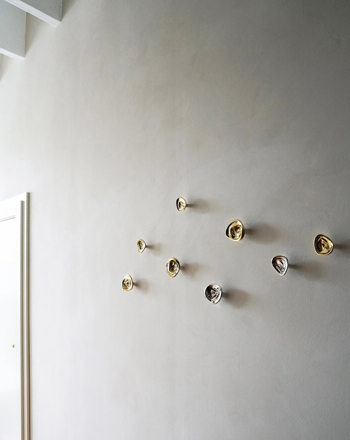 Ripple Hook - Large - Brass — arranged on textured wall in modern setting
