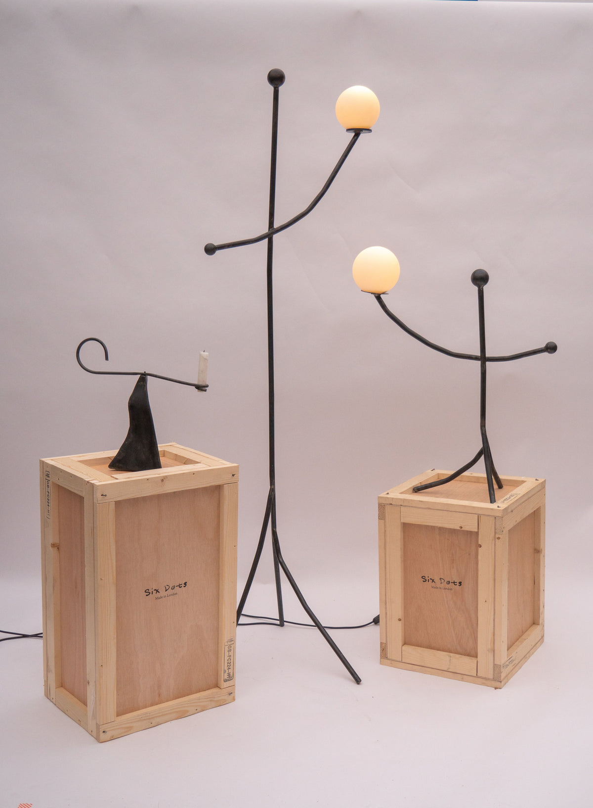 Black sculptural candle holder with glowing orbs on wooden crates