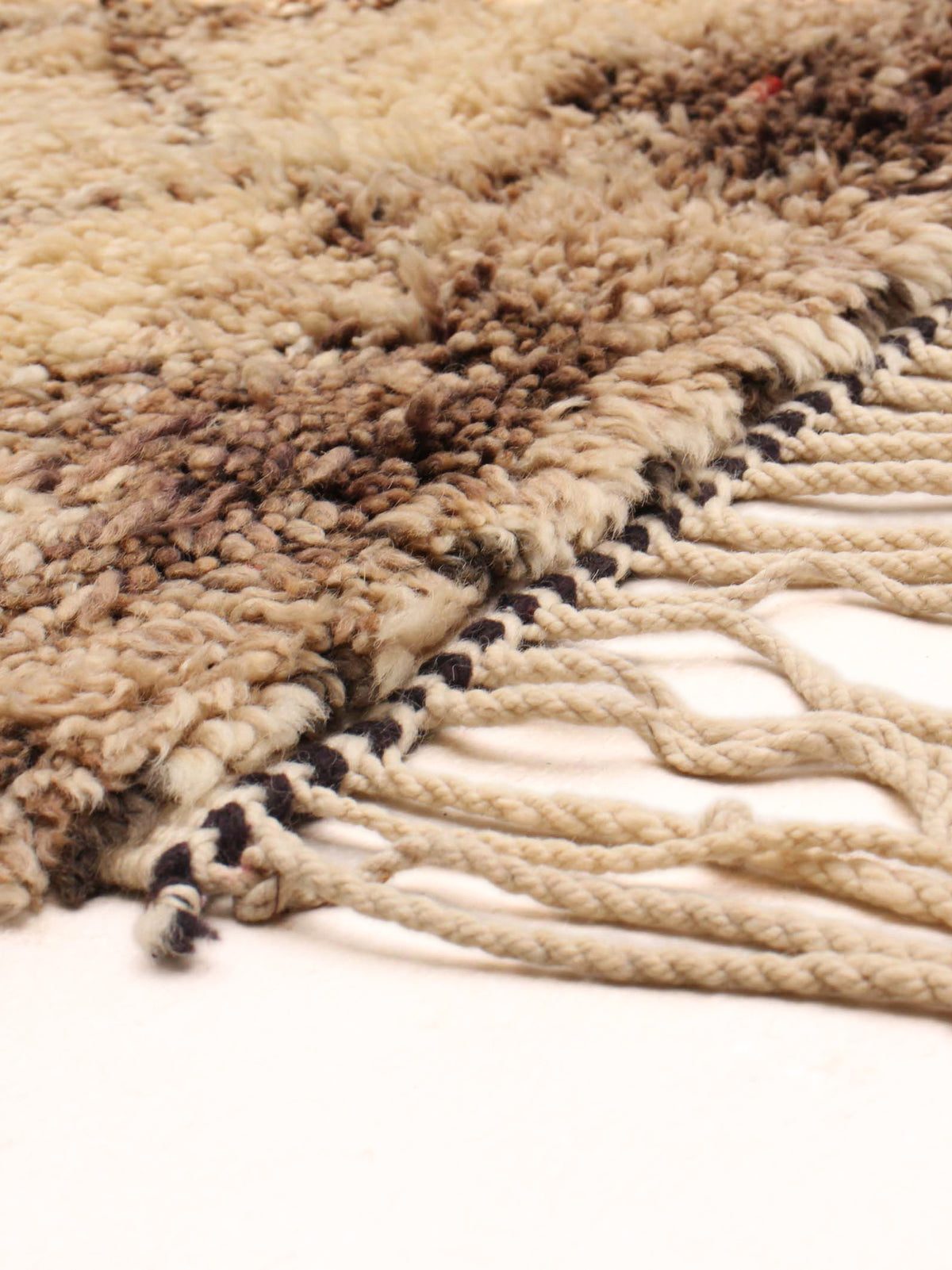 Close-up of the catalog:three Moroccan Berber Rug in Ivory (196 x 295 cm) features thick, textured wool fibers and loosely twisted, spread fringe, displayed on a light surface.