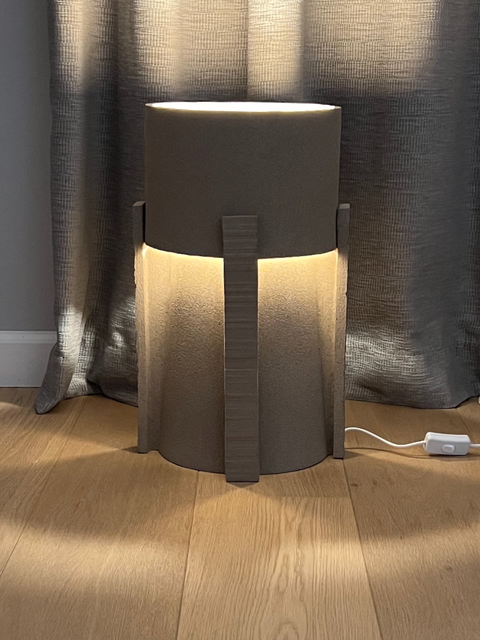 Hold ceramic table lamp with cylindrical form and warm lighting detail