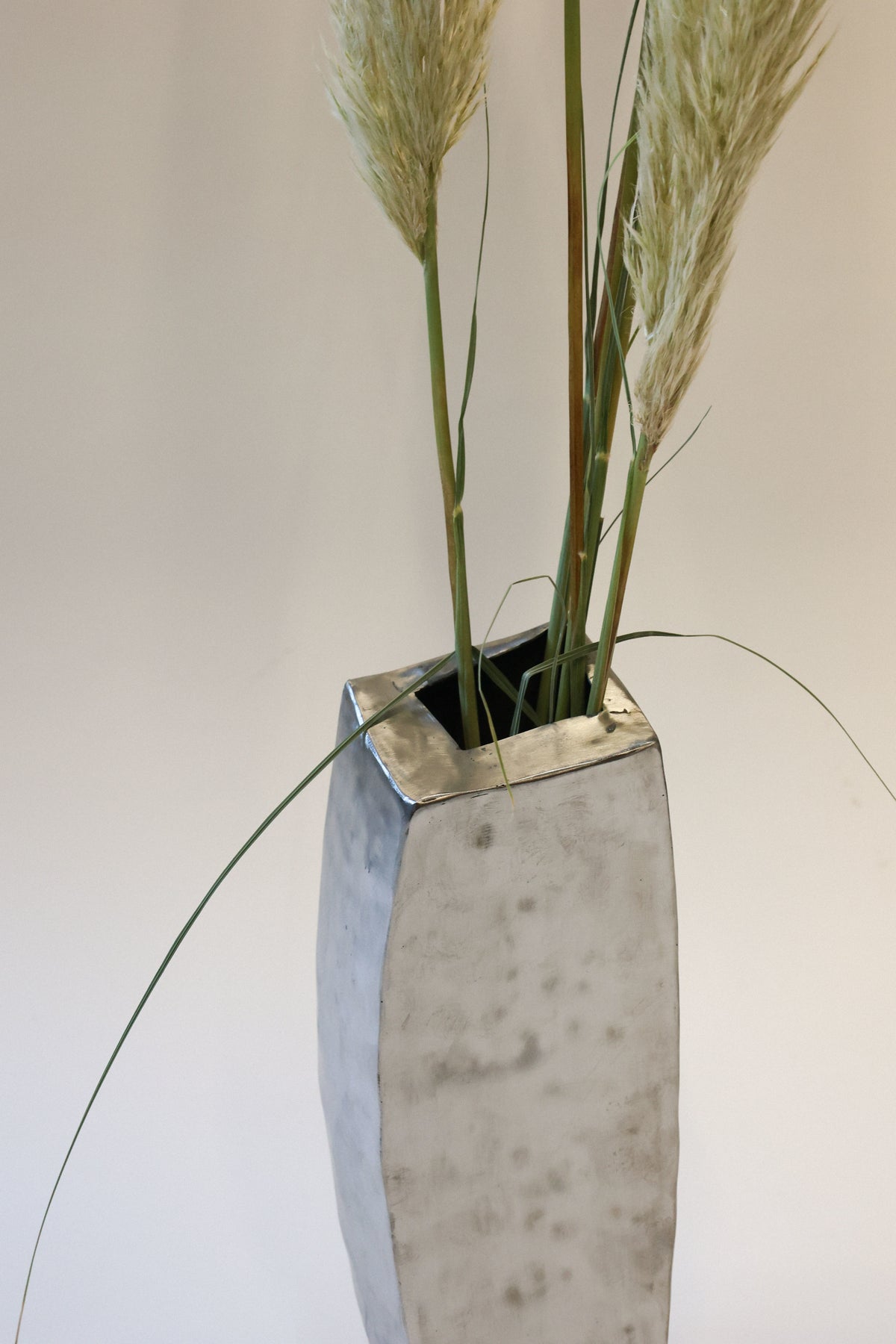 Hammered steel vase with dried pampas grass stems detail view