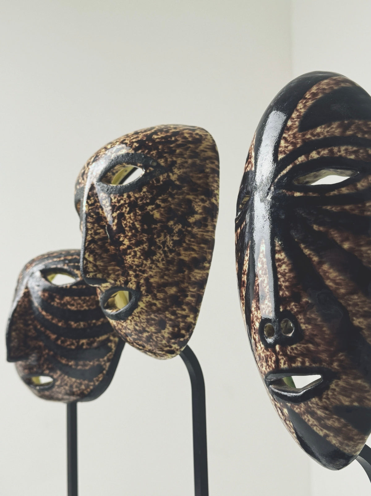 Close-up detail of two ceramic masks showing intricate patterns