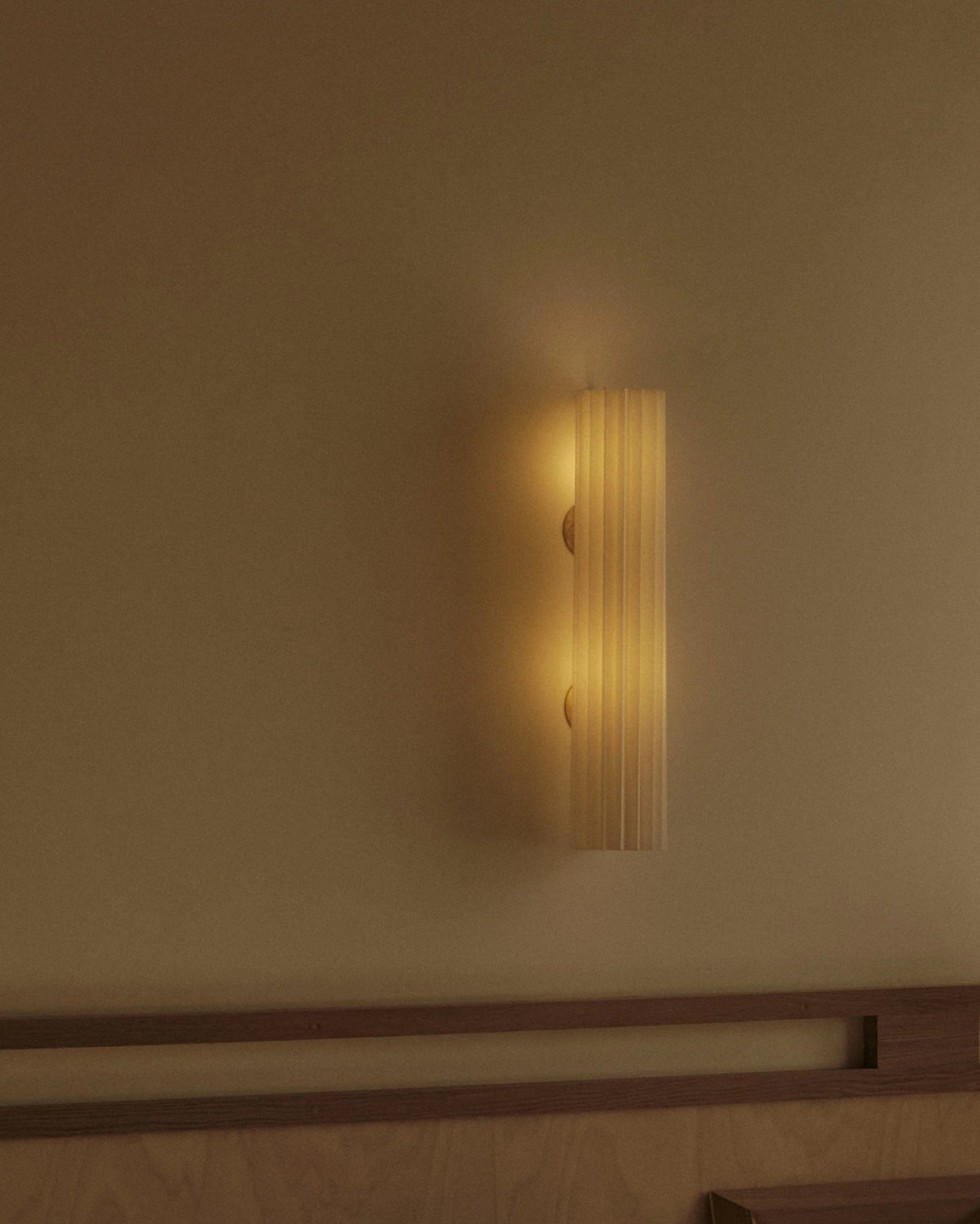 Golden cylindrical wall light casting warm ambient glow on wall