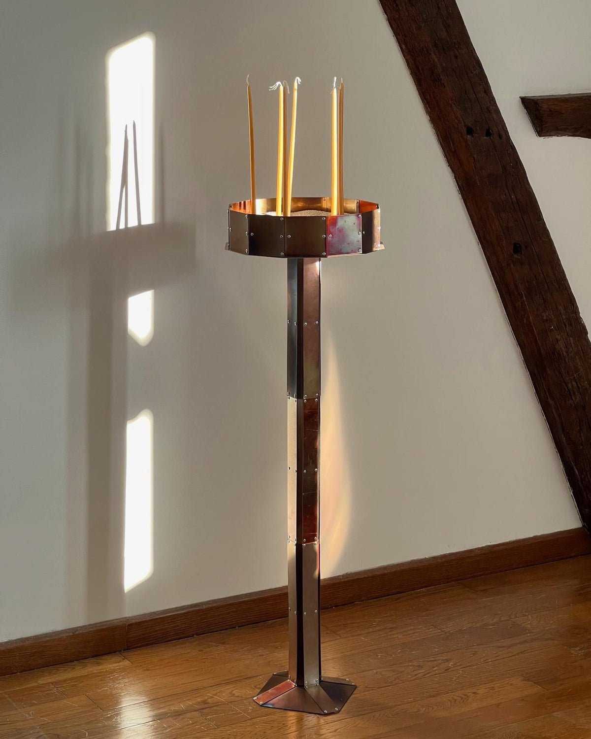 Modern copper candleholder with tall stand holding four tapered candles