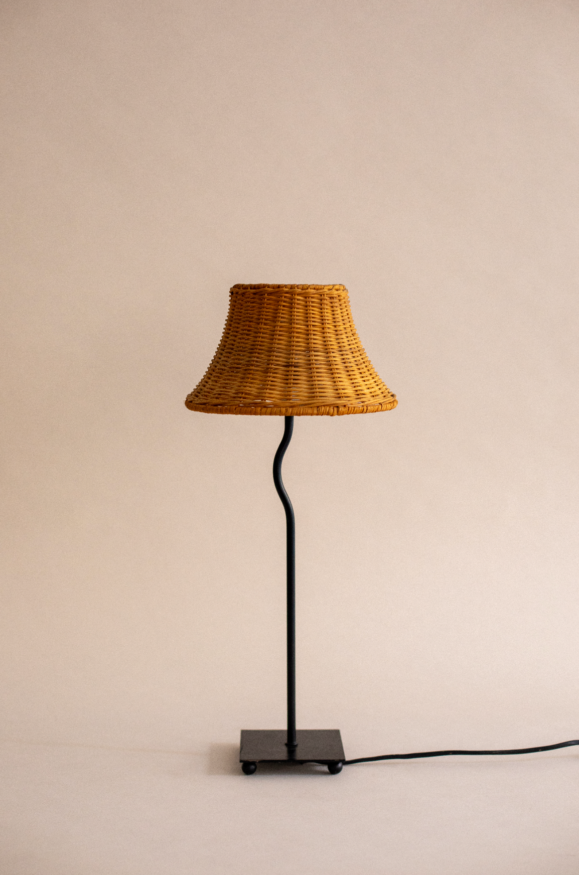 Woven rattan table lamp with black metal stand by SÒLER
