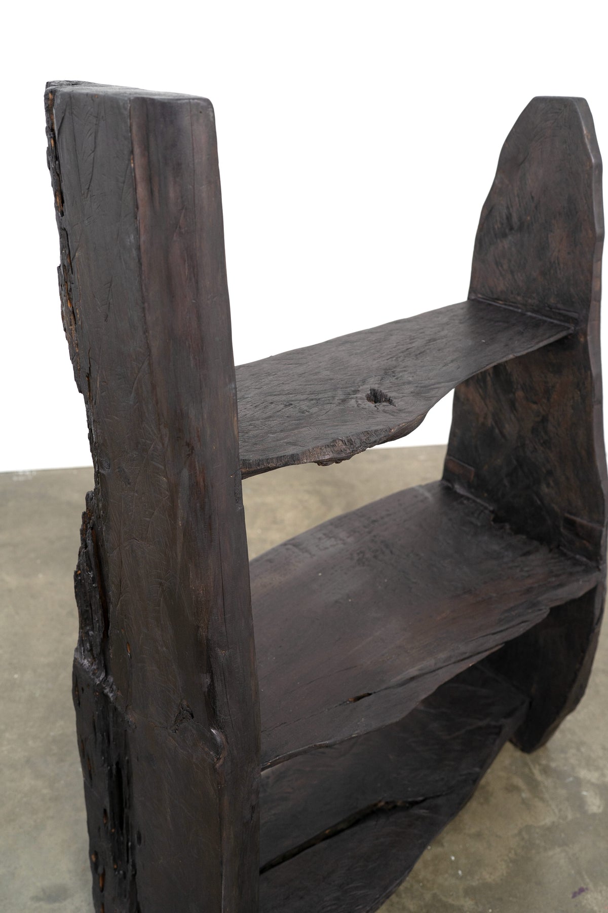Weathered dark wood brutalist bookcase with thick slab shelves