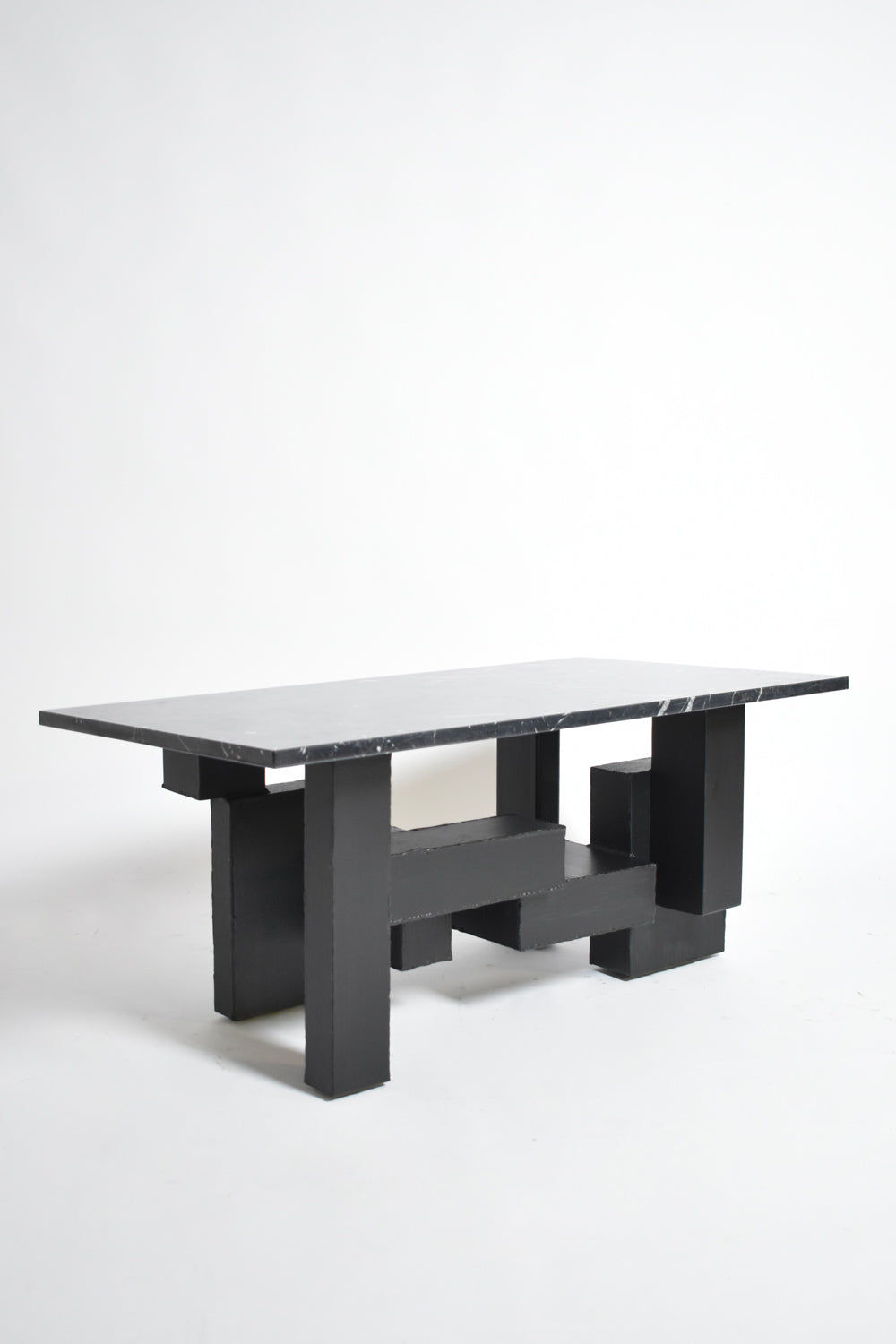 The Cubist Iron and Marble Coffee Table by Barracuda Interiors (1980s) features a thick black marble top and geometric iron legs, showcased against a plain white background.