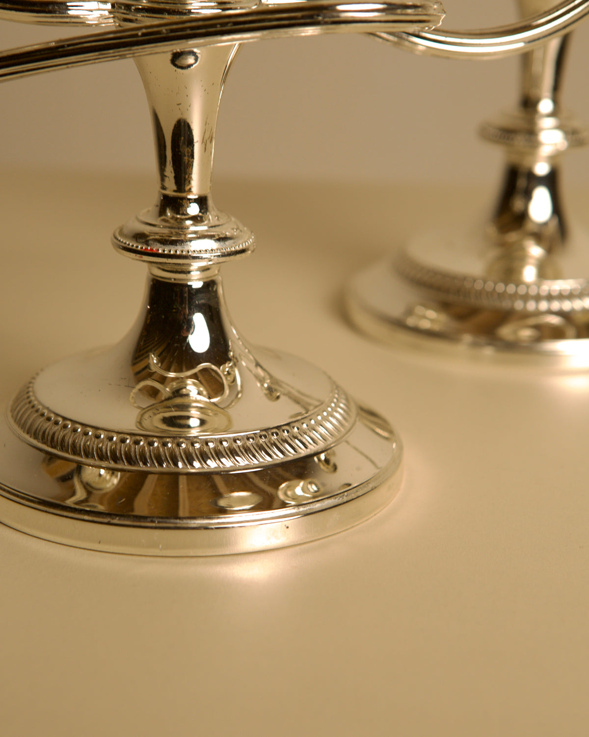Pair of Italian metal "Medusa" candlesticks, 1980s — close-up of polished silver bases
