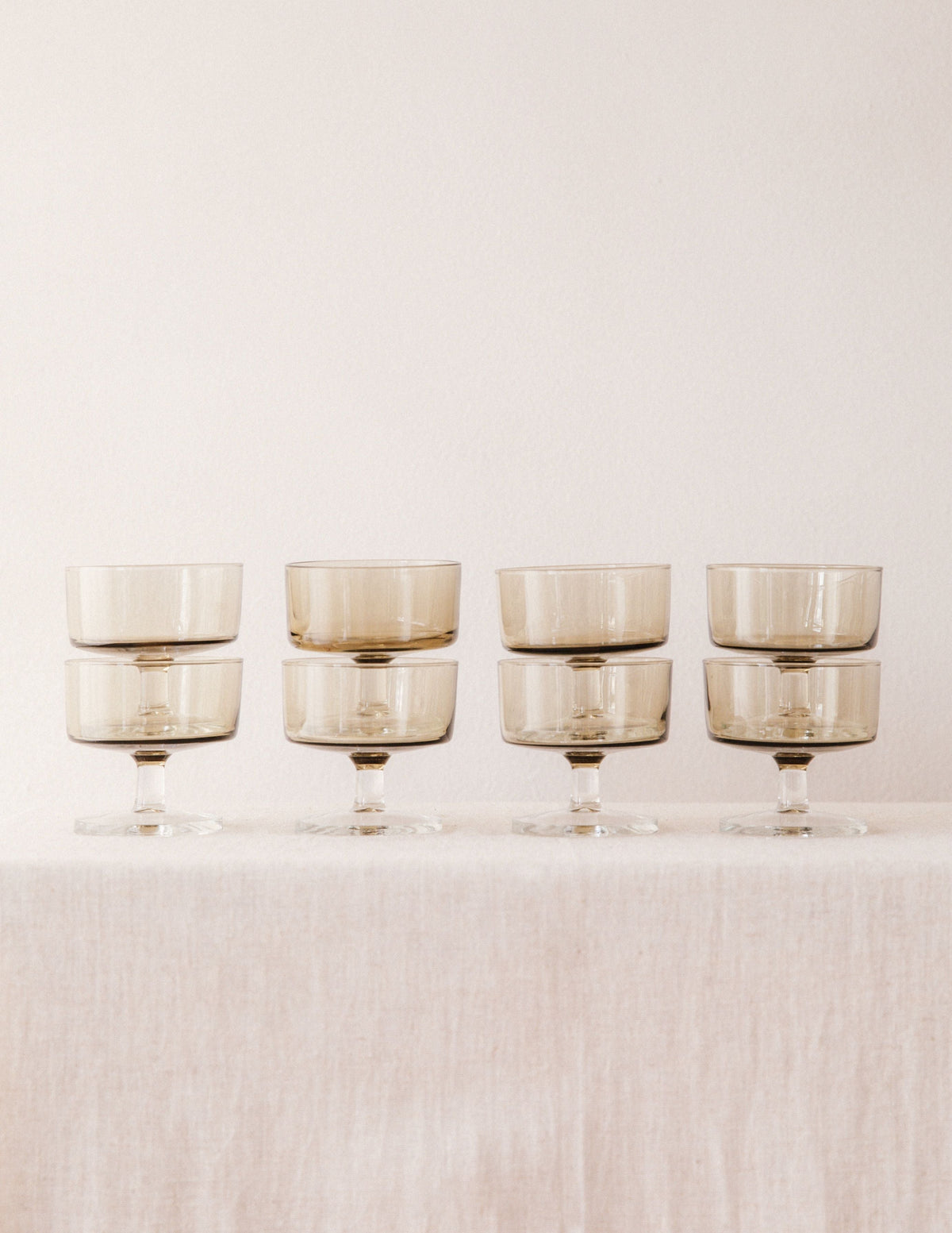 Set of eight stacked smoked glass champagne coupes with clear stems