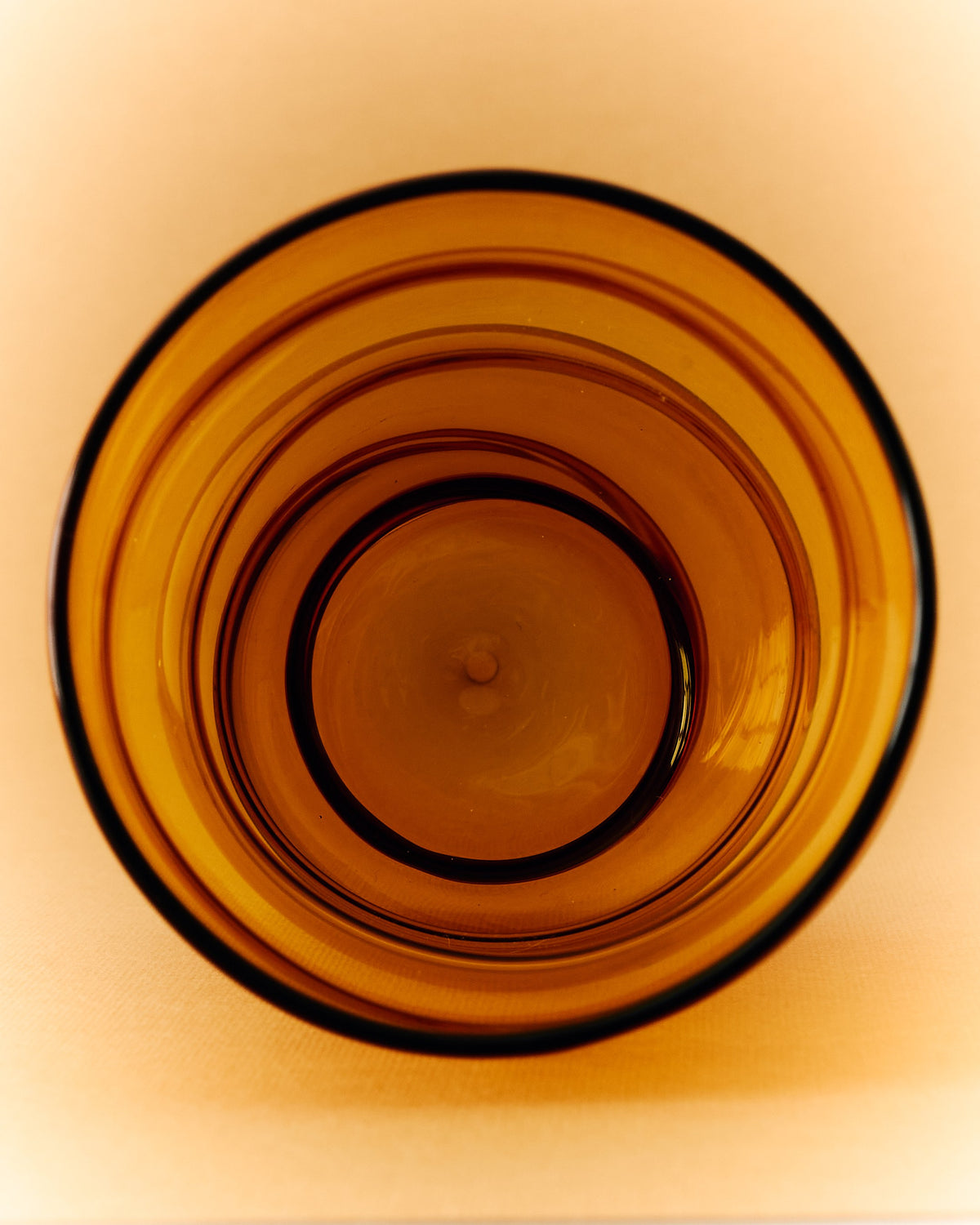 Amber glass bowl detail showing concentric ridged pattern of Paguro drinkware