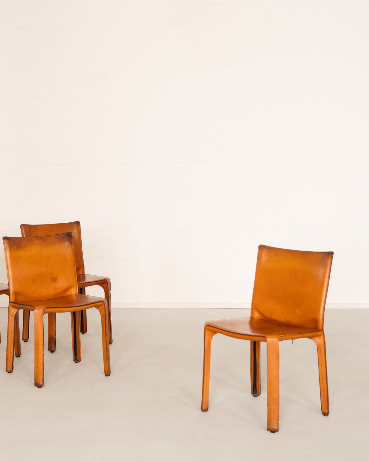 Cab 412 Chair Set by Mario Bellini for Cassina — close-up of orange leather chair in minimalist setting