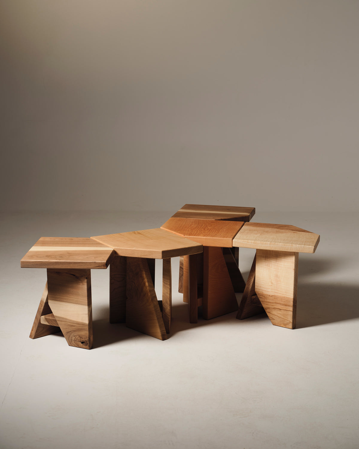 Set of five sculptural maple wood stools with curved seats and arch bases