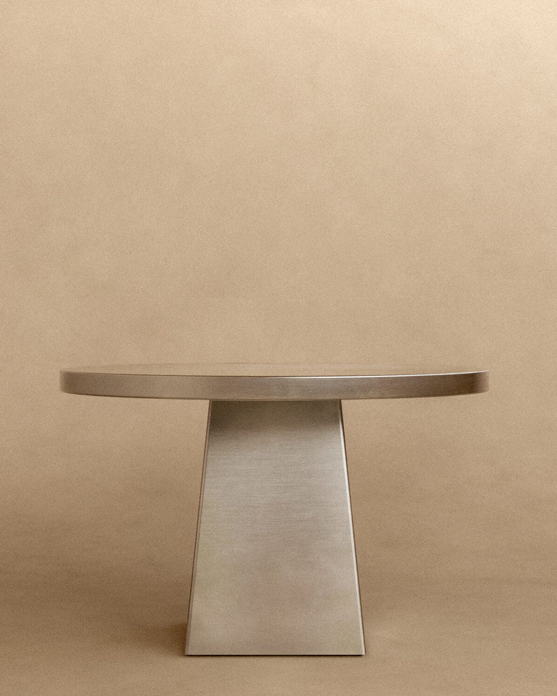 Round brushed stainless steel dining table with tapered pedestal base