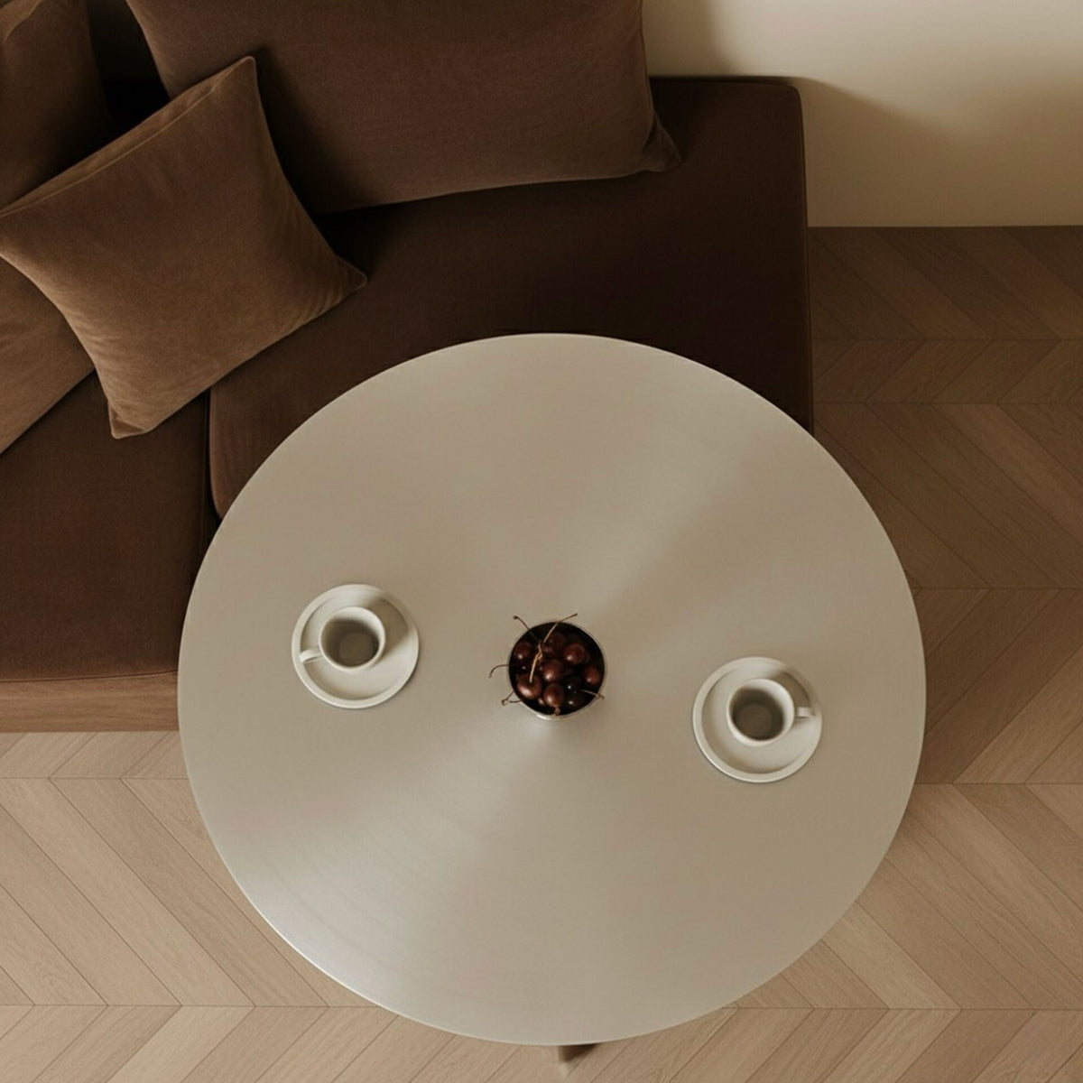 Round stainless steel coffee table styled with espresso cups and cherries, top view